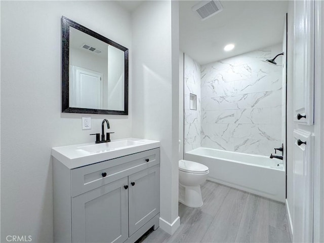 full bathroom with tiled shower / bath, vanity, toilet, and hardwood / wood-style floors