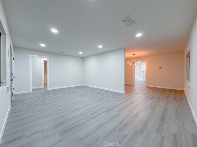 empty room with a chandelier and light wood-type flooring