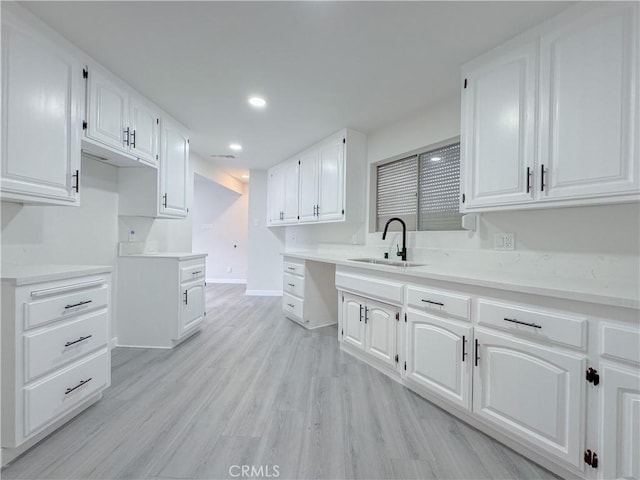 kitchen with sink, white cabinets, and light hardwood / wood-style flooring