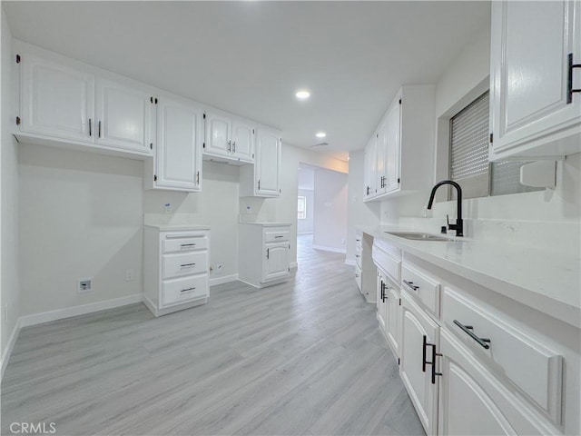 kitchen featuring sink, light hardwood / wood-style flooring, and white cabinets