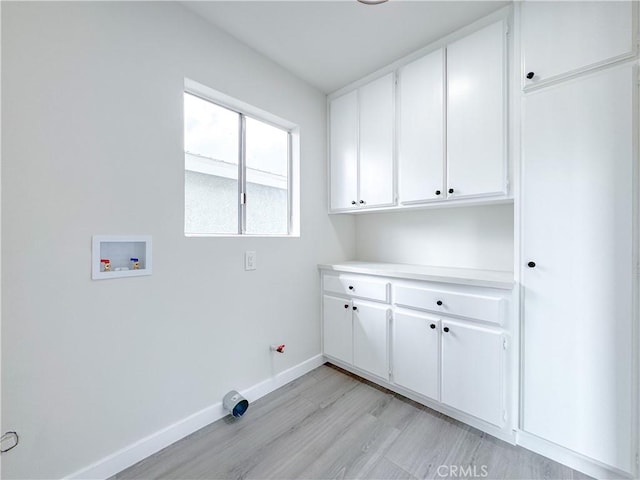 laundry room featuring hookup for a washing machine, light hardwood / wood-style floors, and cabinets