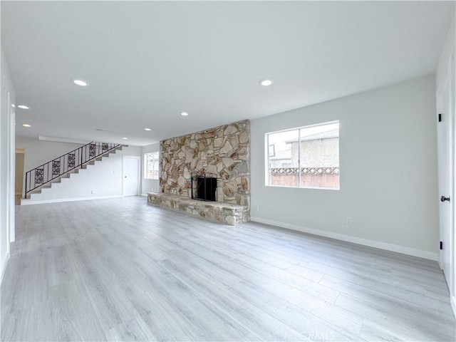 unfurnished living room with a stone fireplace and light hardwood / wood-style flooring