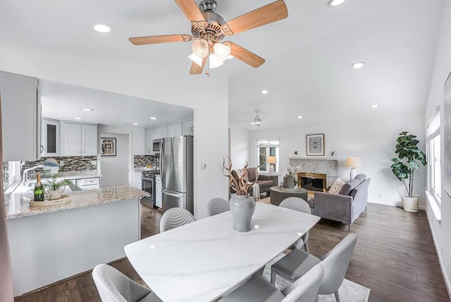 dining area with dark hardwood / wood-style floors, lofted ceiling, and a premium fireplace