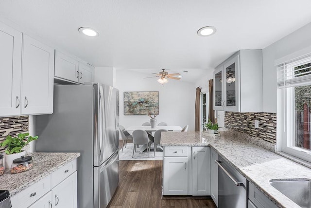 kitchen with light stone counters, white cabinetry, stainless steel appliances, and kitchen peninsula