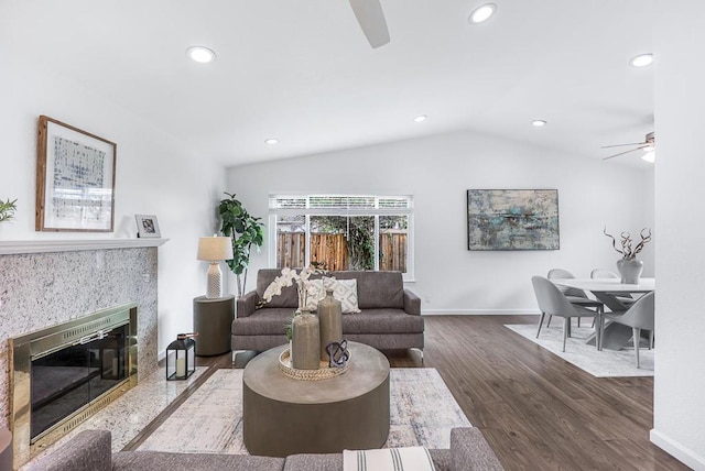 living room with lofted ceiling, a premium fireplace, dark hardwood / wood-style floors, and ceiling fan