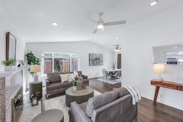 living room with a premium fireplace, lofted ceiling, dark hardwood / wood-style floors, and ceiling fan