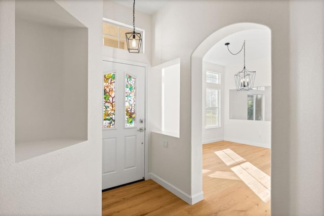 entrance foyer with a high ceiling, wood-type flooring, and a notable chandelier