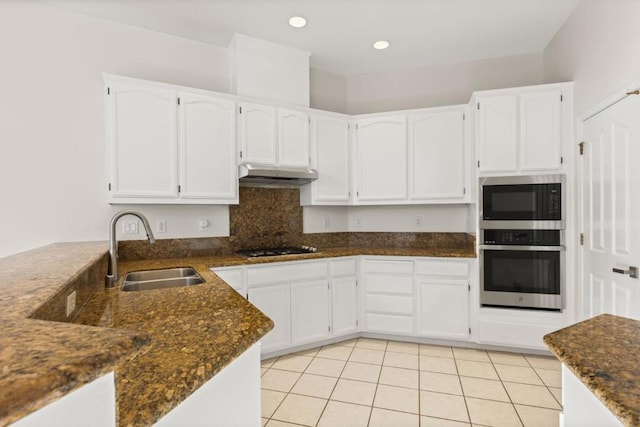 kitchen featuring light tile patterned flooring, appliances with stainless steel finishes, sink, white cabinets, and dark stone counters