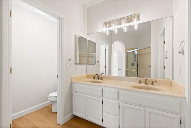 bathroom with vanity, hardwood / wood-style floors, a shower with shower door, and toilet