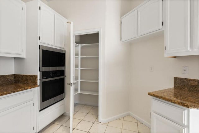 kitchen with white cabinetry, dark stone counters, and light tile patterned flooring