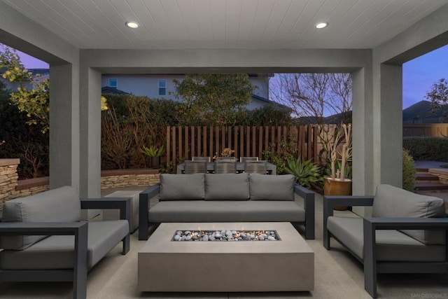 patio terrace at dusk with an outdoor living space with a fire pit