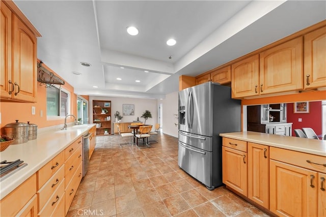 kitchen with sink, a tray ceiling, kitchen peninsula, and appliances with stainless steel finishes