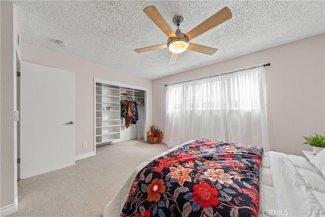 bedroom featuring ceiling fan, light colored carpet, a closet, and a textured ceiling