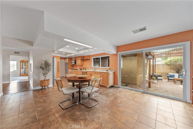 dining space featuring a raised ceiling, sink, and light tile patterned floors