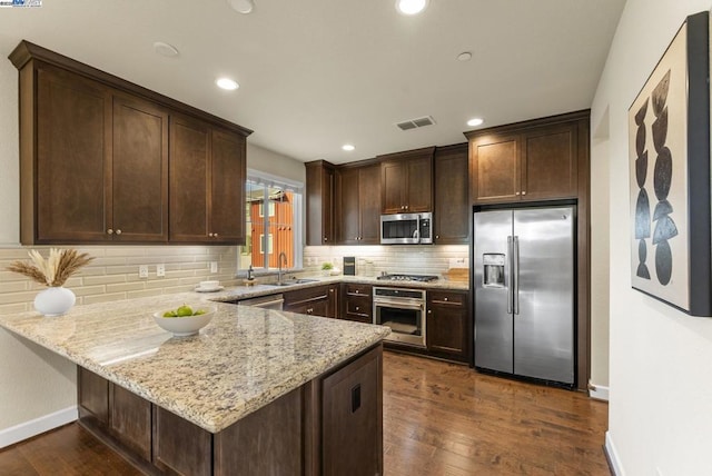 kitchen featuring light stone counters, sink, kitchen peninsula, and appliances with stainless steel finishes