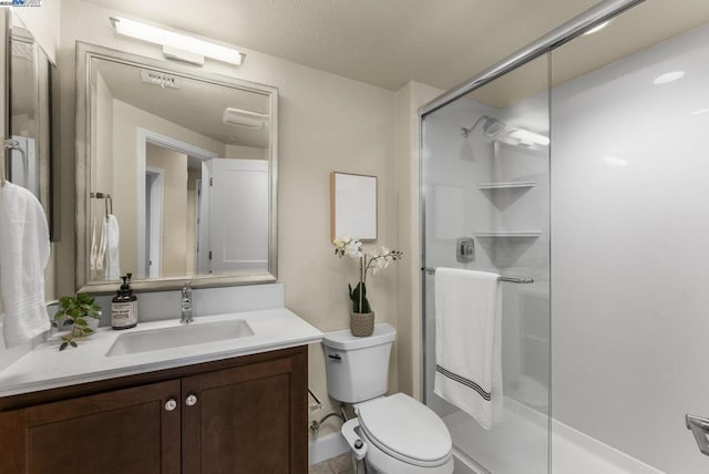 bathroom featuring vanity, a shower with shower door, and toilet