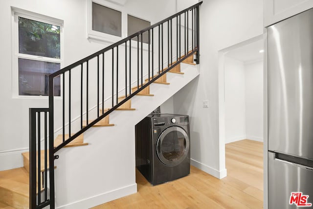 clothes washing area with washer / clothes dryer and light hardwood / wood-style floors