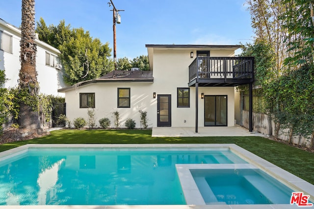 back of property with a balcony, a swimming pool with hot tub, a patio area, and a lawn