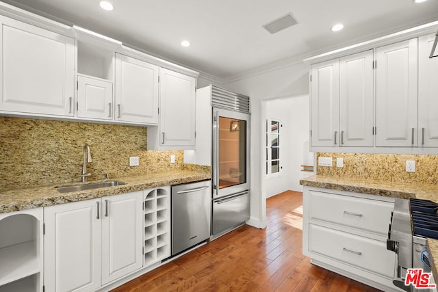 kitchen with appliances with stainless steel finishes, dark hardwood / wood-style floors, sink, white cabinets, and crown molding