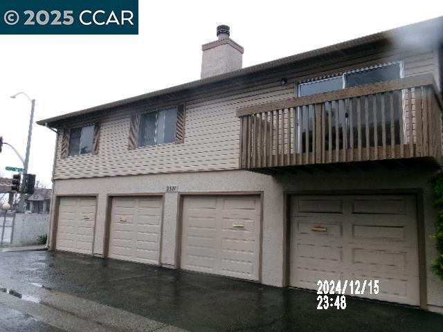 rear view of property featuring a garage and a balcony