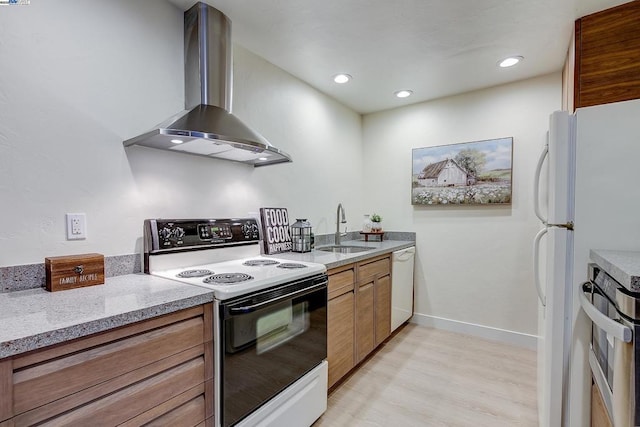 kitchen with wall chimney range hood, white appliances, light hardwood / wood-style flooring, sink, and light stone counters