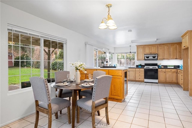 kitchen with light tile patterned floors, gas range gas stove, an inviting chandelier, hanging light fixtures, and kitchen peninsula