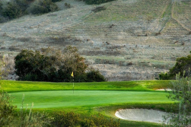 view of community featuring view of golf course and a lawn