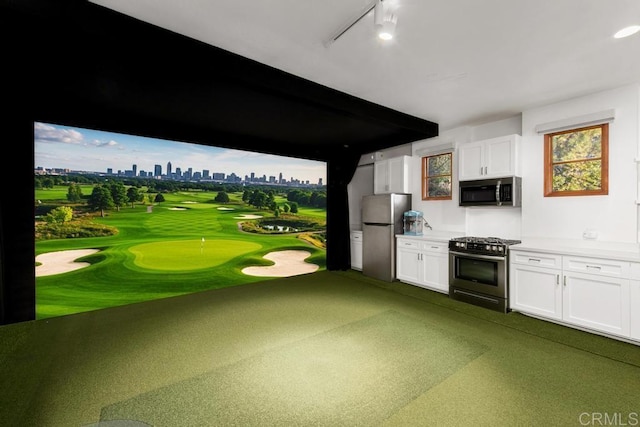 kitchen featuring white cabinetry, appliances with stainless steel finishes, a city view, and golf simulator