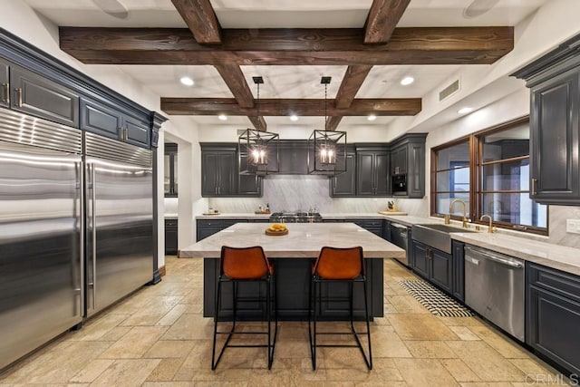 kitchen featuring appliances with stainless steel finishes, a center island, stone tile flooring, and tasteful backsplash