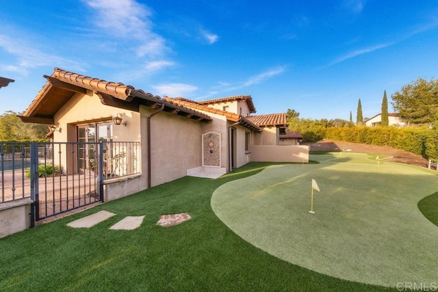 back of house featuring a gate, stucco siding, a tile roof, and fence