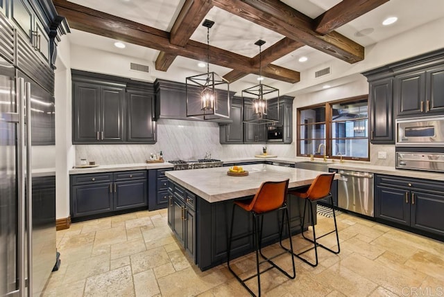 kitchen with stone tile floors, built in appliances, beam ceiling, and visible vents