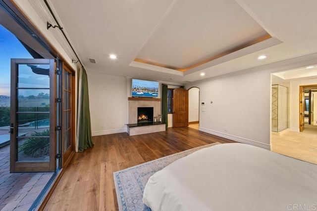 bedroom with a tray ceiling, wood finished floors, and crown molding