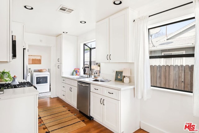 kitchen featuring washer / clothes dryer, sink, stainless steel appliances, and white cabinets