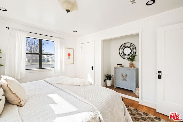 bedroom with ornamental molding and hardwood / wood-style floors