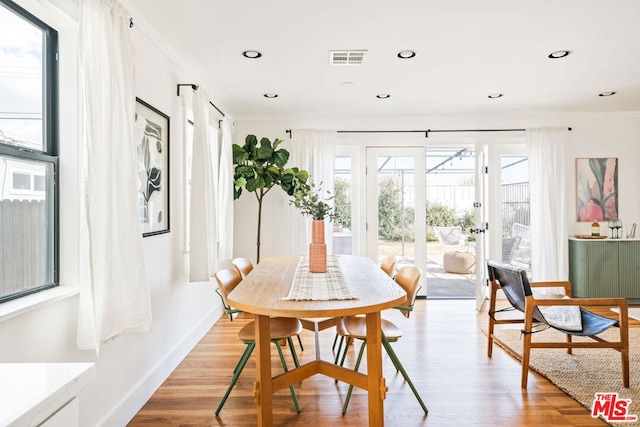 dining space with crown molding and light wood-type flooring