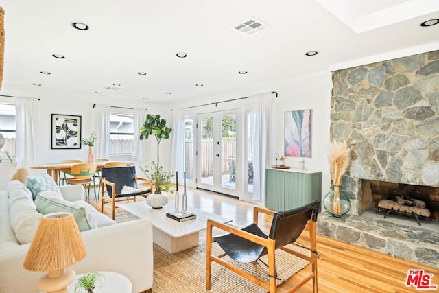 living room with french doors, a fireplace, and light hardwood / wood-style flooring