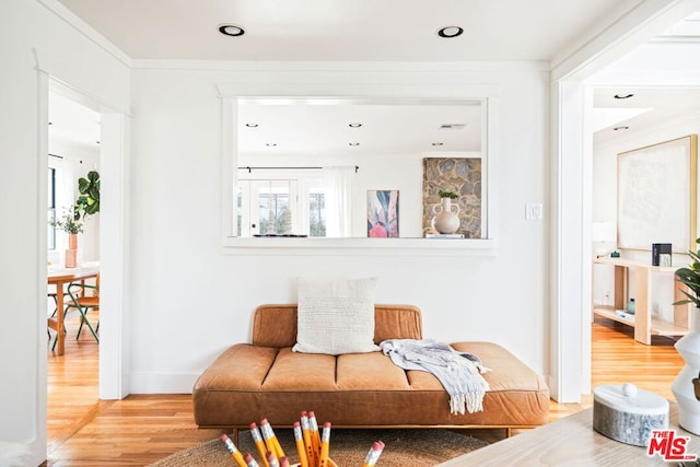 sitting room with ornamental molding and wood-type flooring