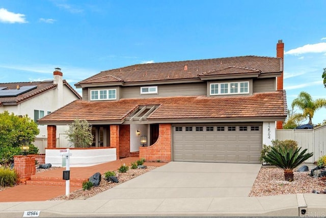 traditional-style house with driveway, a garage, a chimney, fence, and brick siding