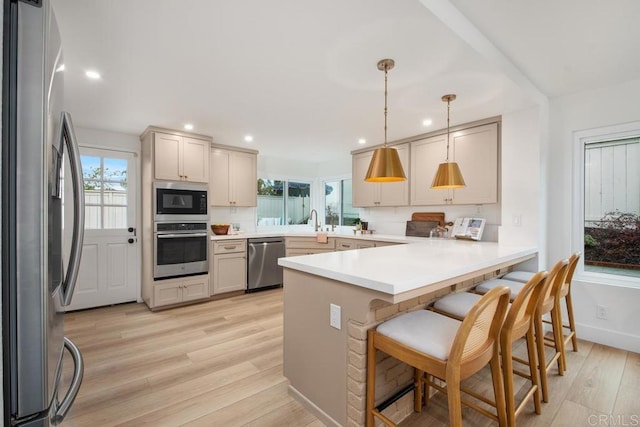 kitchen featuring a peninsula, light wood-style floors, a healthy amount of sunlight, and stainless steel appliances