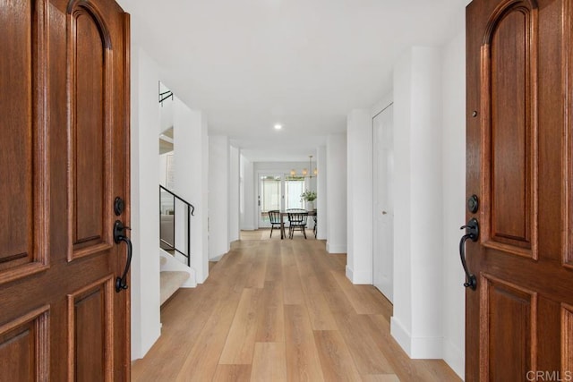 foyer with light wood finished floors, stairway, and baseboards