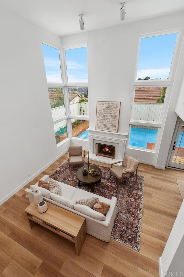 living area featuring a warm lit fireplace, baseboards, and wood finished floors