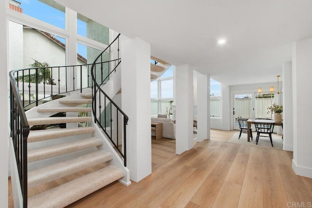 stairway with a notable chandelier, baseboards, and wood finished floors