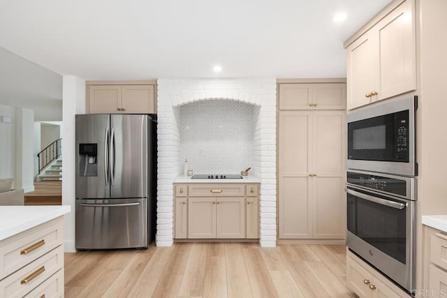 kitchen with tasteful backsplash, appliances with stainless steel finishes, light countertops, light wood-type flooring, and recessed lighting