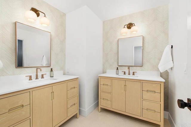 full bathroom featuring two vanities, a sink, and baseboards