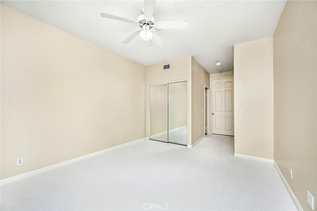 unfurnished bedroom featuring light carpet, a closet, and ceiling fan