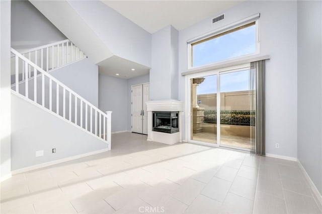 unfurnished living room with a high ceiling and light tile patterned flooring