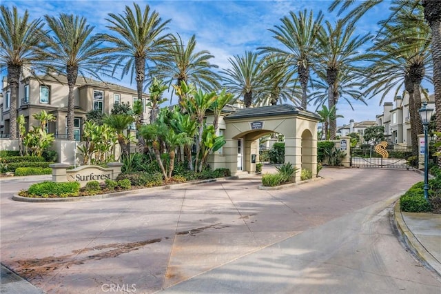 view of road with a gated entry, a residential view, curbs, and a gate