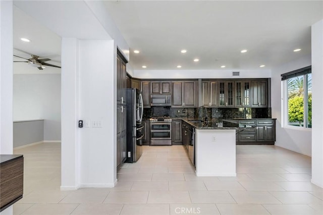 kitchen featuring a kitchen island, appliances with stainless steel finishes, sink, dark stone countertops, and backsplash