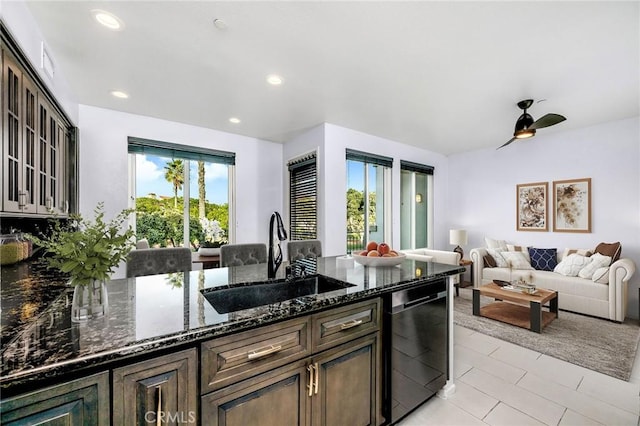 kitchen with a sink, dark stone counters, dishwasher, and recessed lighting