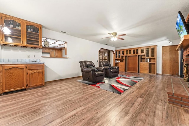 living room with ceiling fan, bar area, and light hardwood / wood-style floors